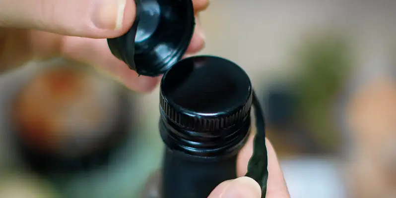 A shrink sleeve being peeled off an oil bottle